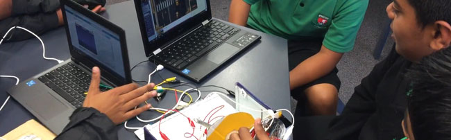 students creating with laptops and makey-makey