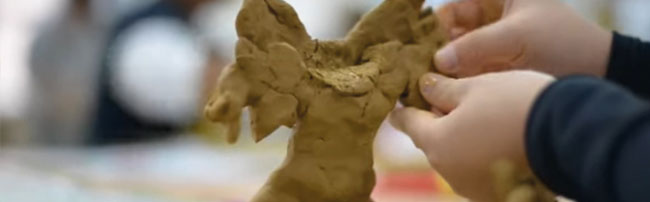 a child modelling a monster out of clay
