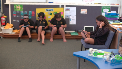 Three students sitting on the floor using iPads and one student sitting on a seat using an iPad