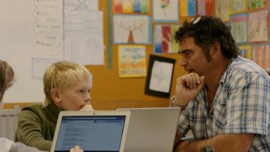 Teacher talking with a student working on his laptop