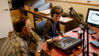 Parent and student sitting at a desk with audio equipment