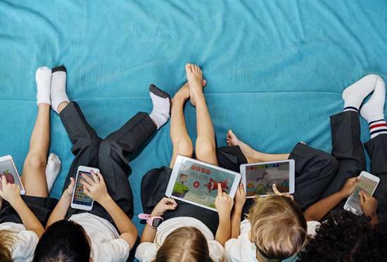 A group of children using phone and tablet devices