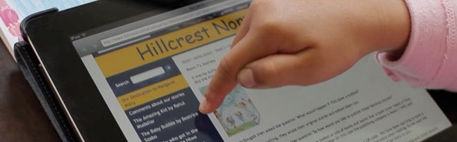 A child's hand using a tablet to access a school website