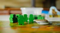 Board game pieces, green meeples and a stack of cardboard tokens
