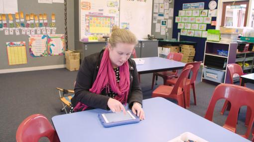 Teacher, Emma Jensen working at a desk on an iPad
