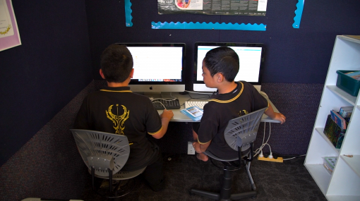 Two boys sitting in front of computers